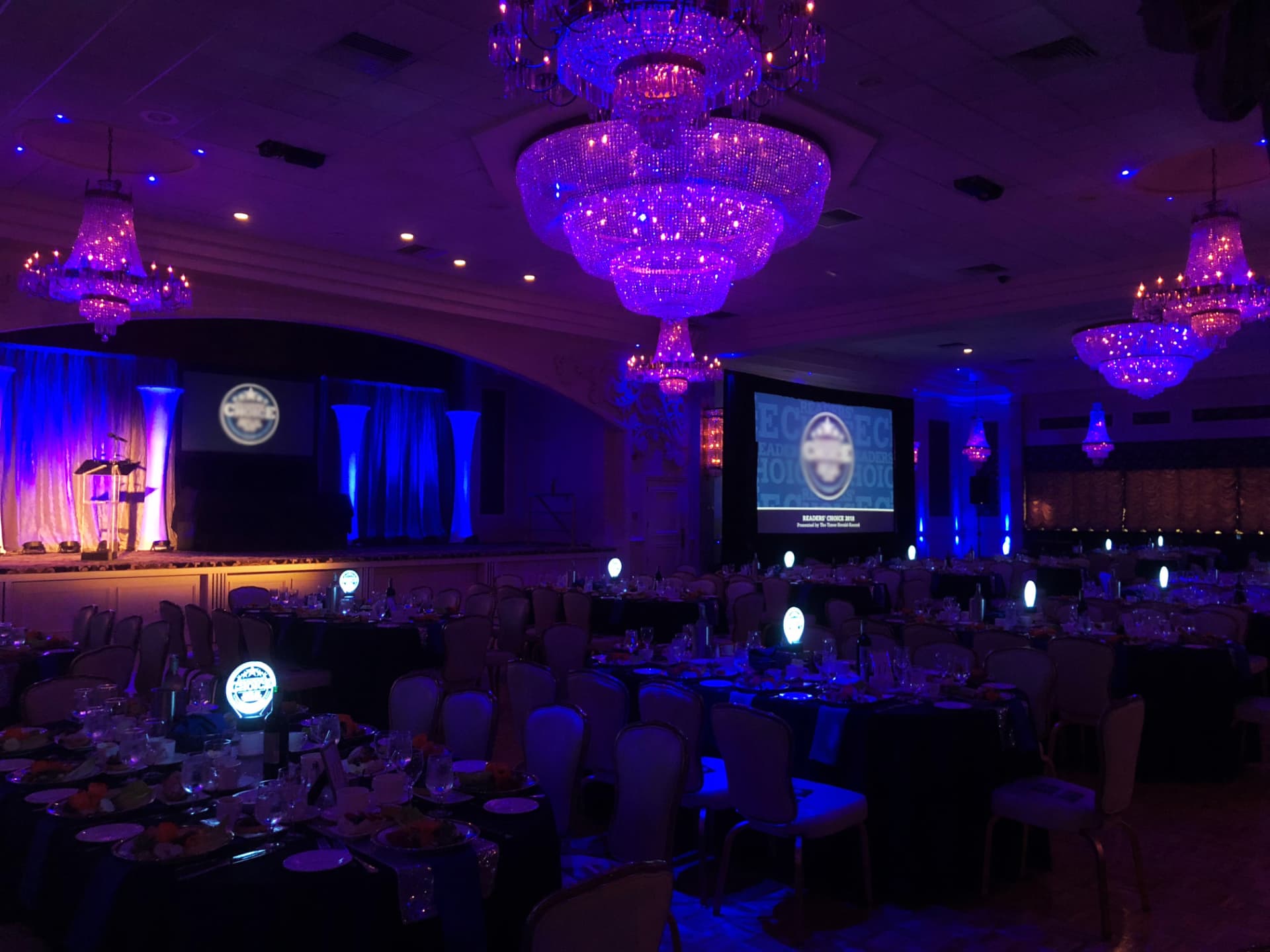 An award show ballroom with chandeliers and a lit stage