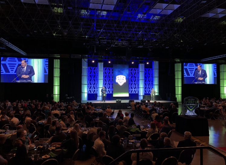 An expo main stage with a speaker and screens