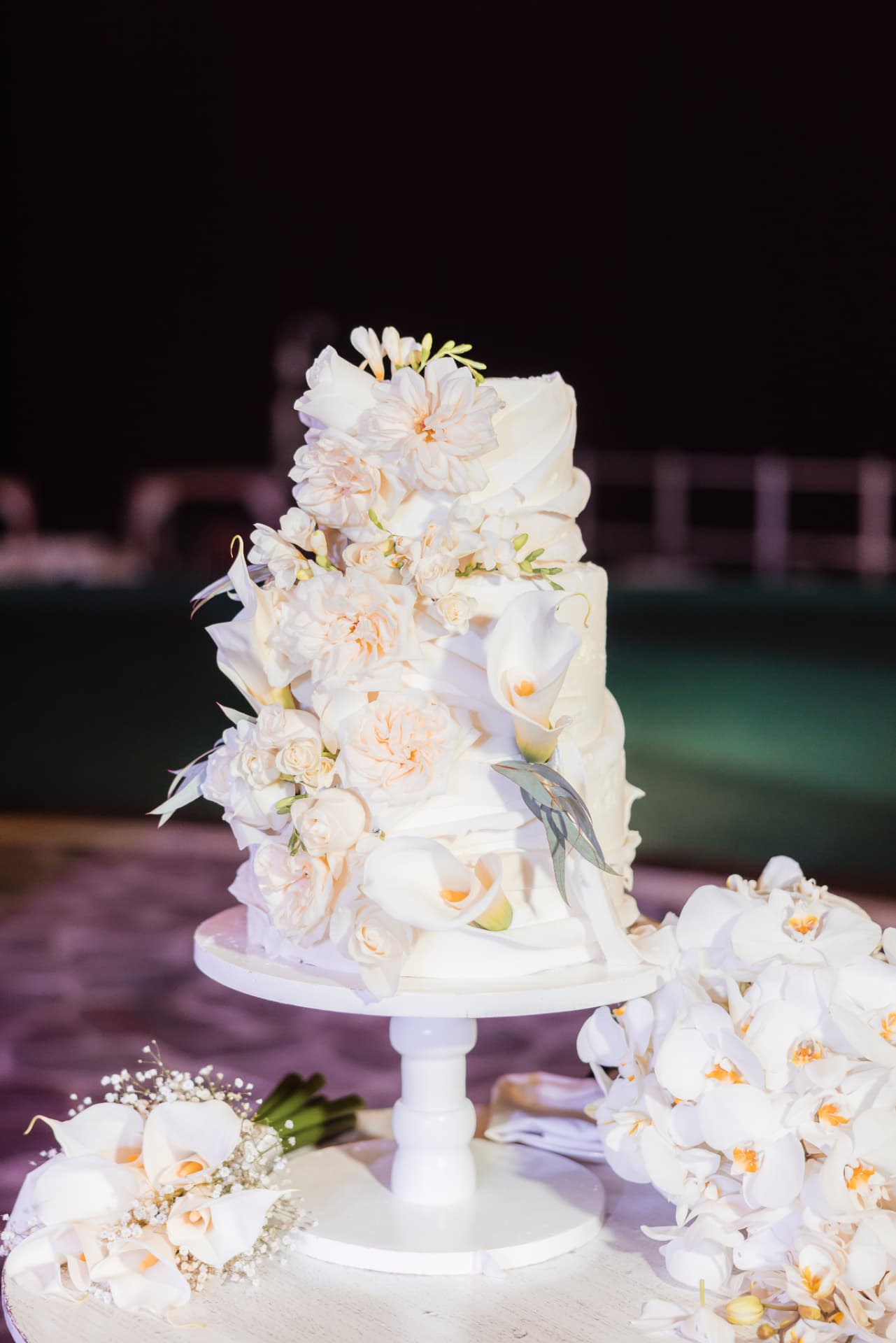 A white floral cake on a poolside terrace
