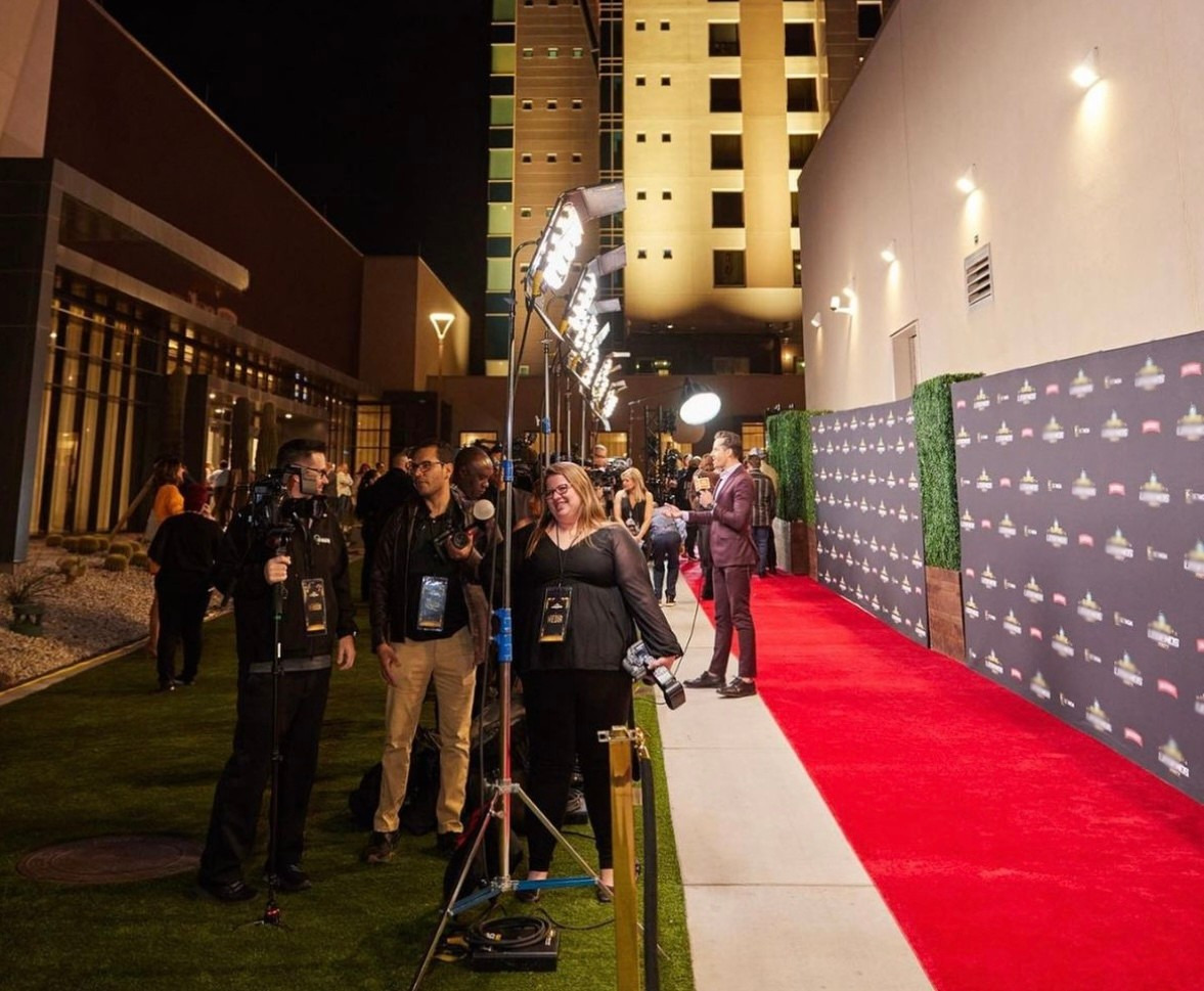A red carpet arrival with media coverage at night