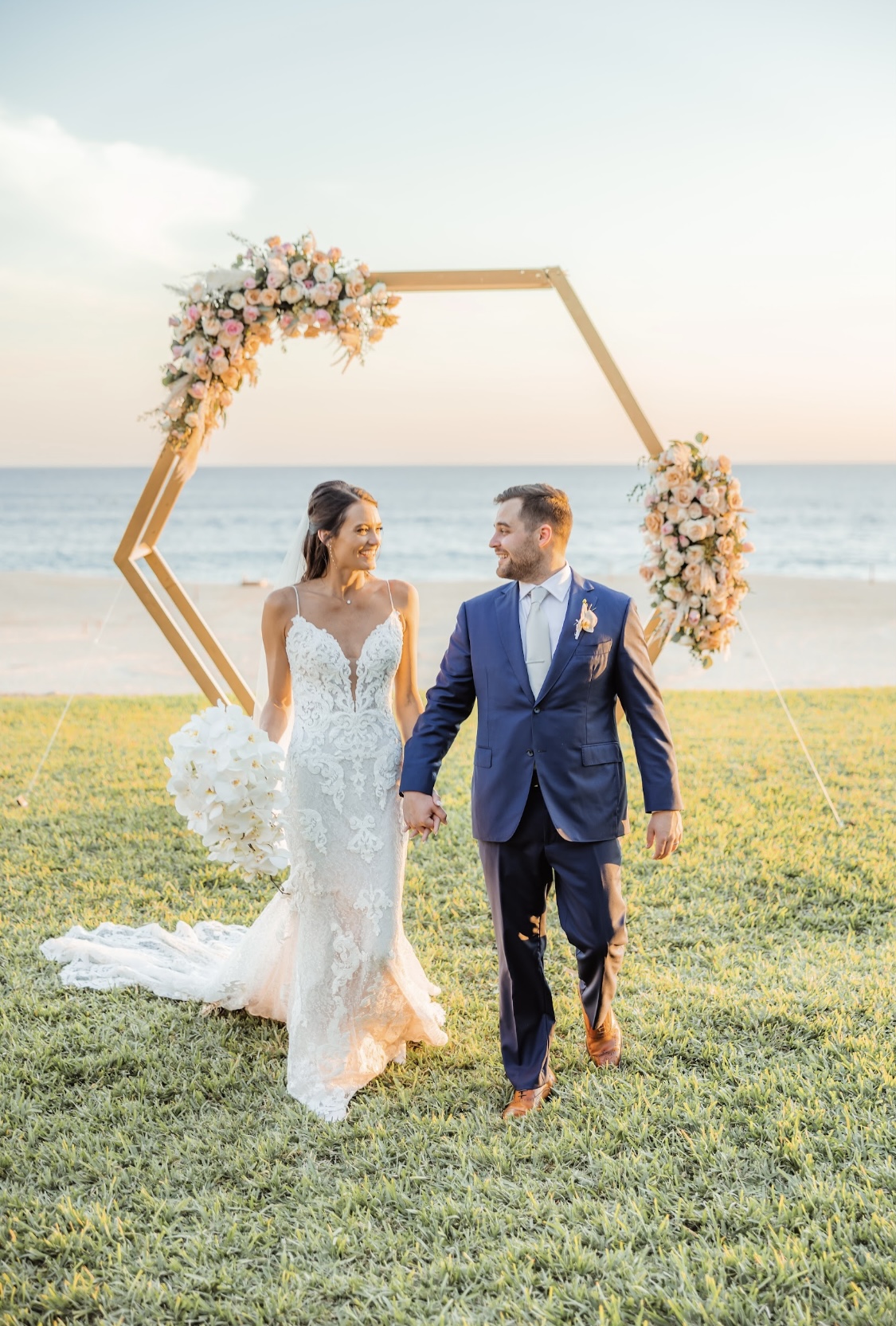 A couple beneath a geometric arch by the sea