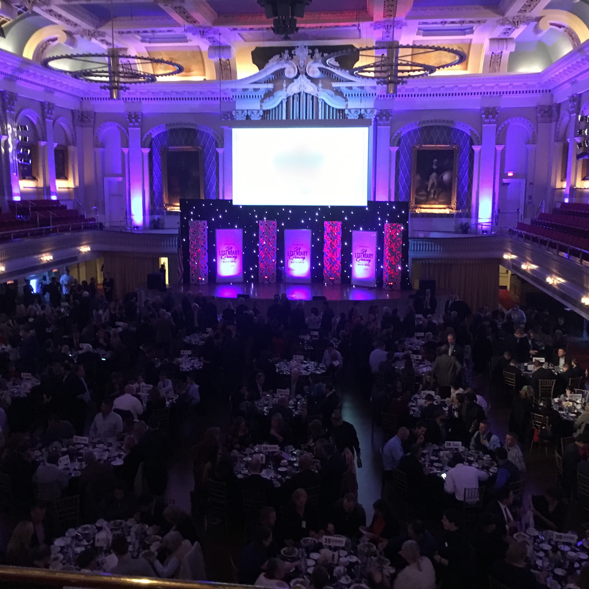 A formal banquet with stage lighting and screens
