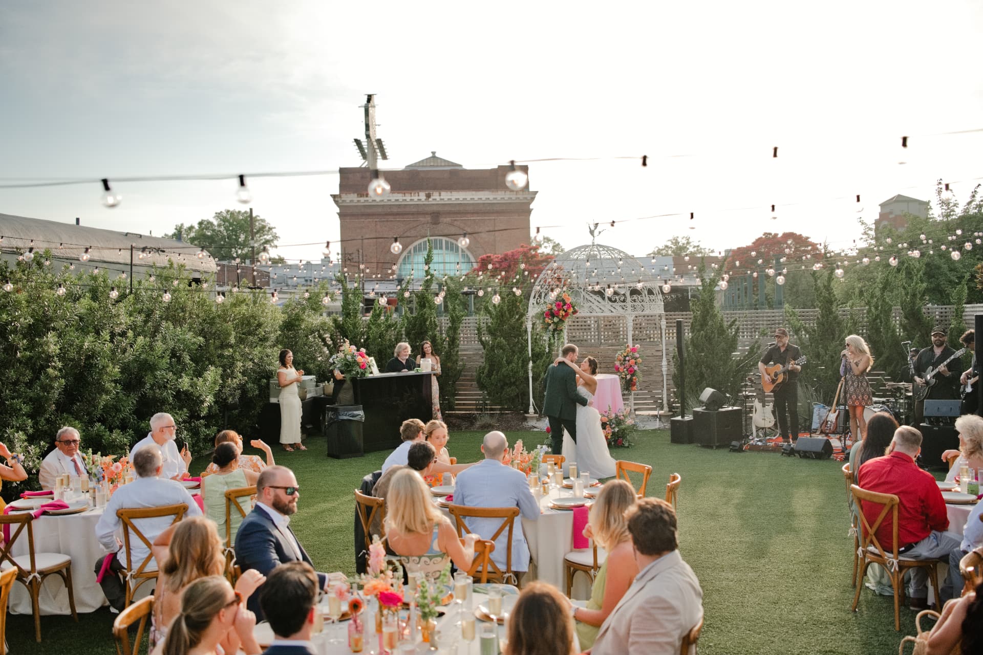 Guests gathered for an outdoor event beneath string lights