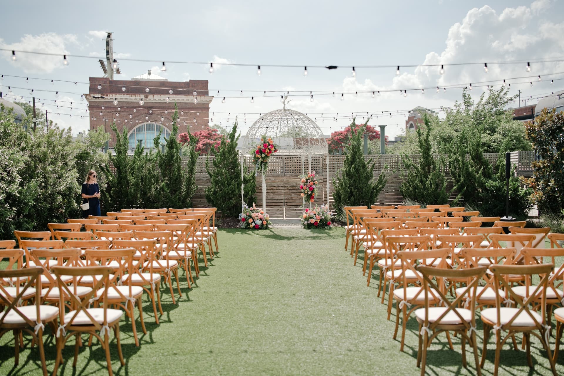 An outdoor ceremony set with rows of wooden chairs
