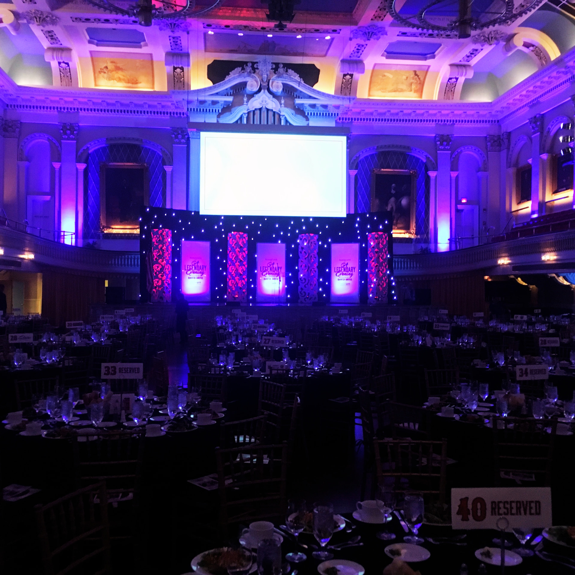 A large event production with a stage, screens, and audience